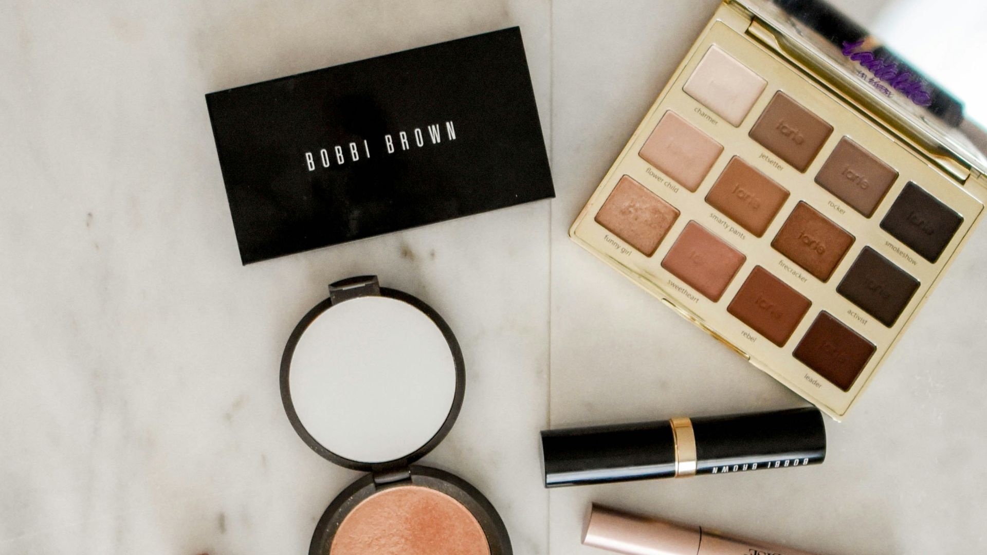 photo of assorted makeup products on gray surface