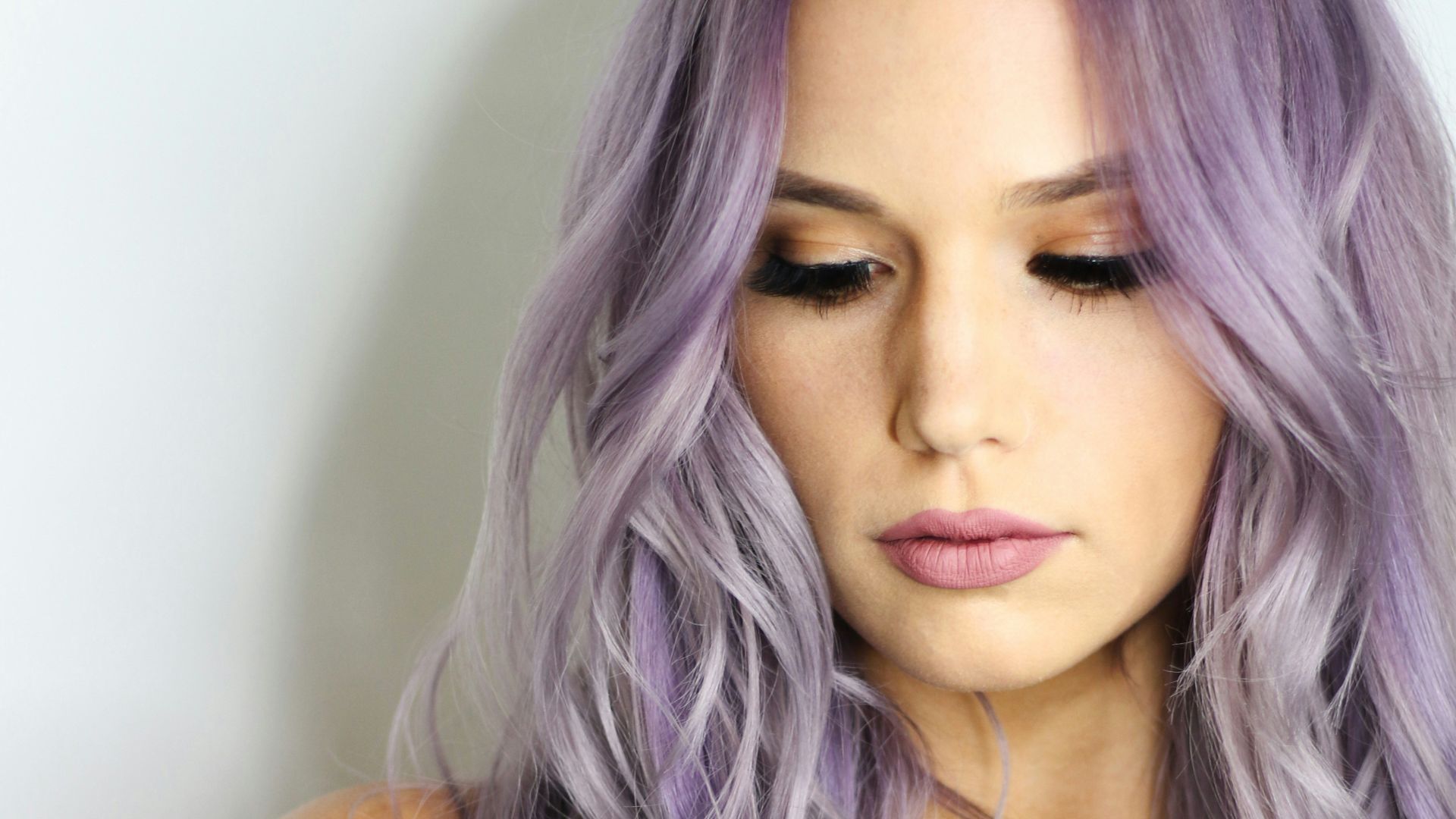 purple haired woman in black top leaning on wall