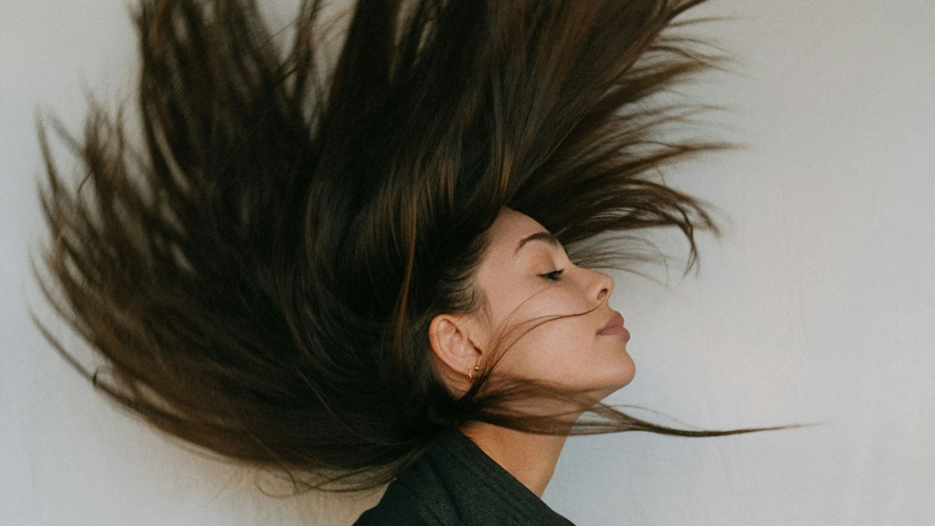 woman in black coat holding her hair