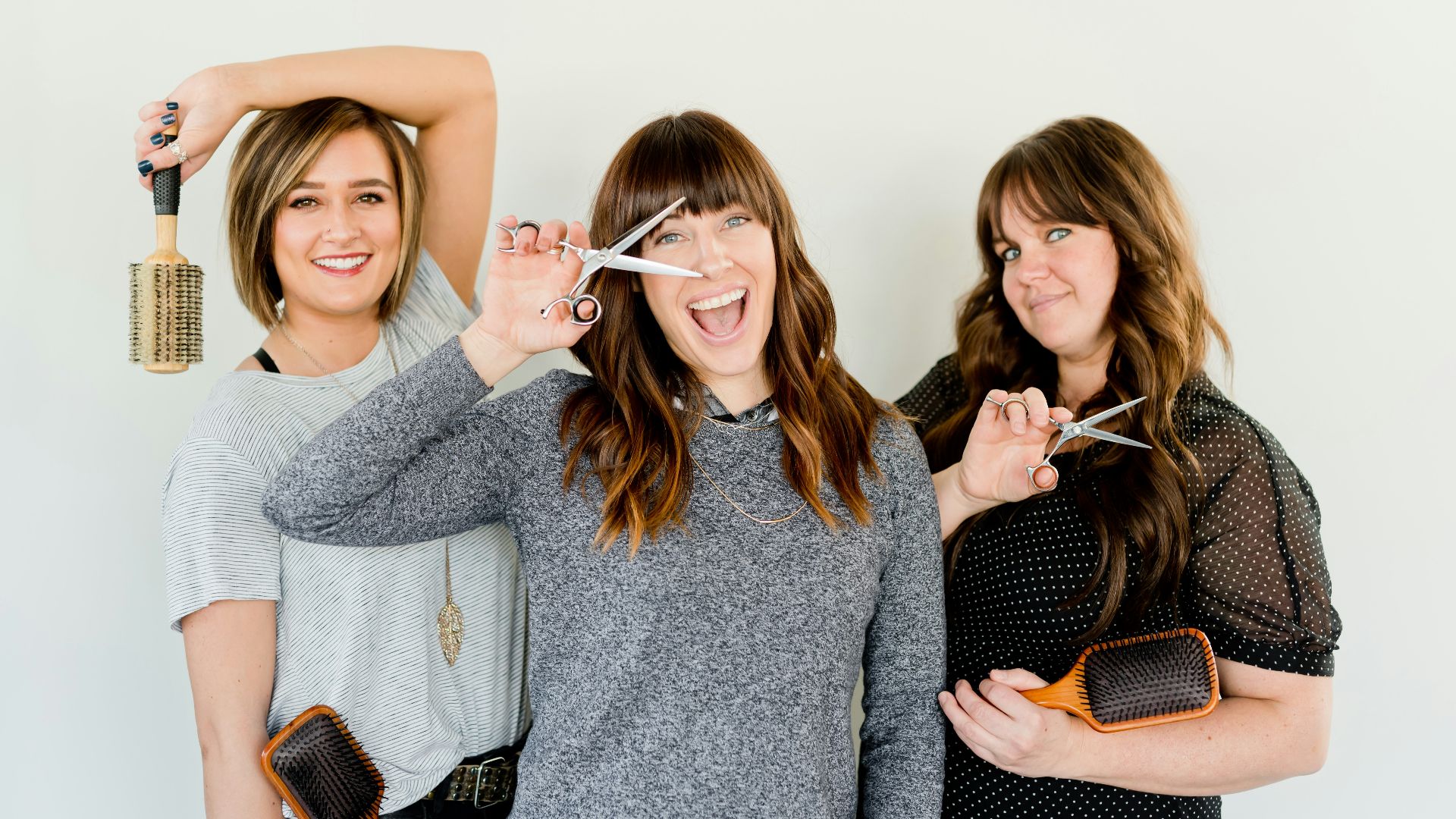 three women holding scissors and brush