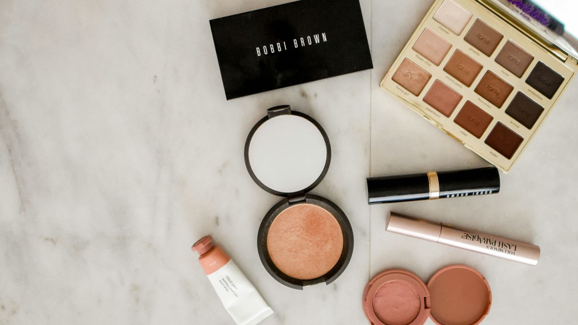 photo of assorted makeup products on gray surface