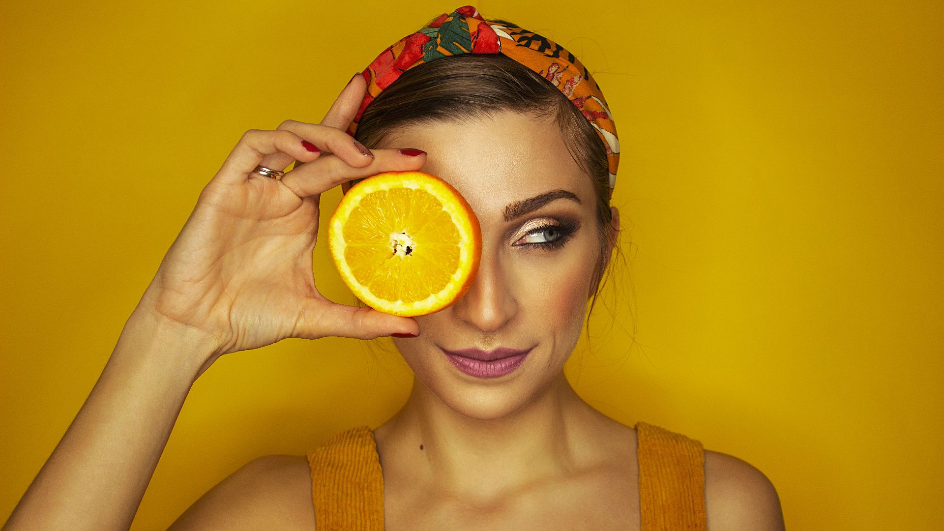 woman covering her right eye with orange slice