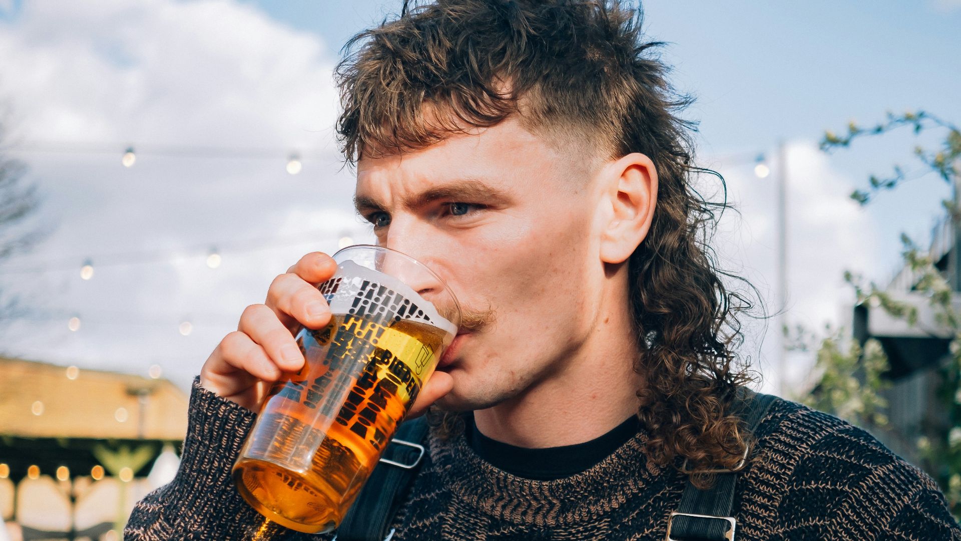 a man with long hair drinking a beer