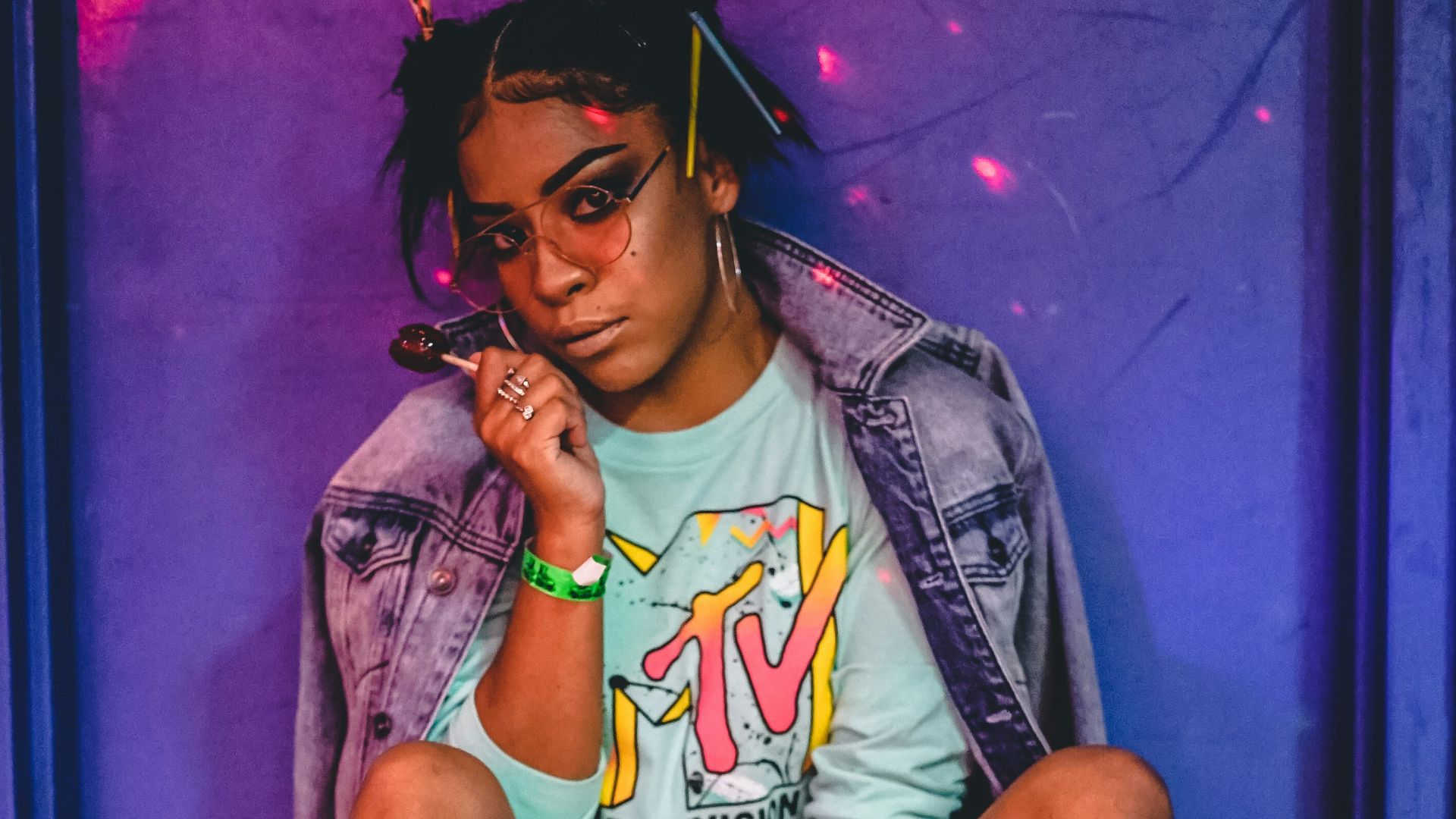 woman sitting wearing roller skates and jacket while holding lollipop