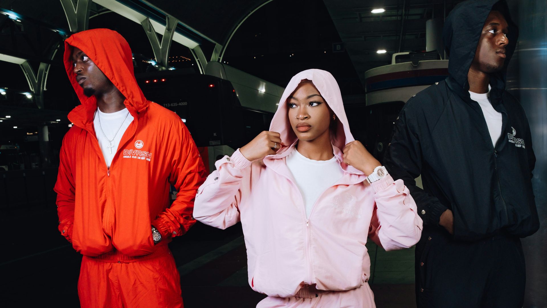 Three people in matching tracksuits outdoors at night.