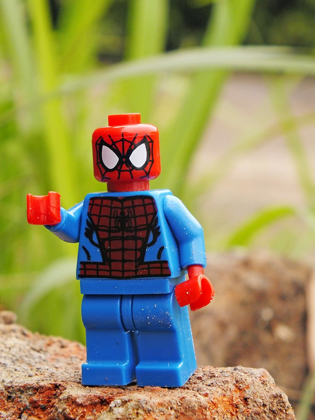 a lego spider - man is standing on a rock
