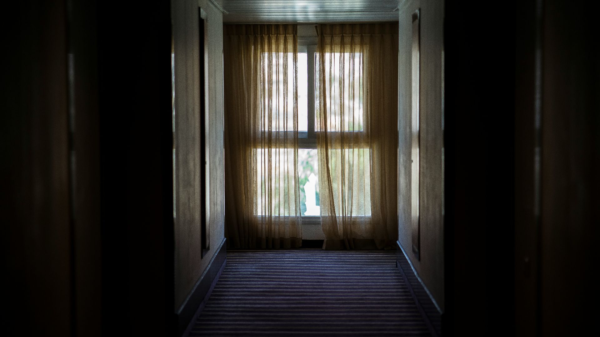 hallway leading to window covered by brown window curtain