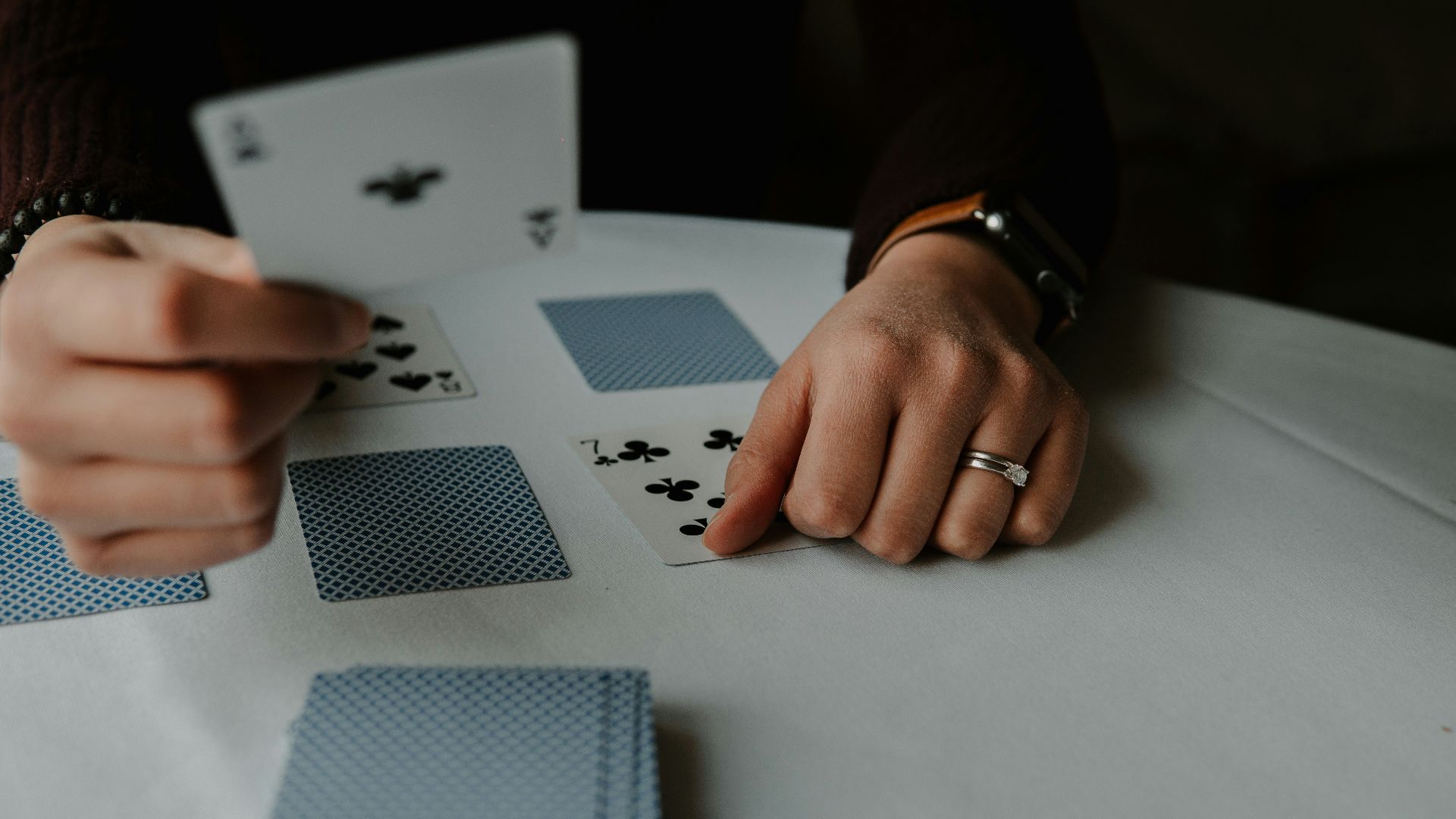 person holding playing cards on white table