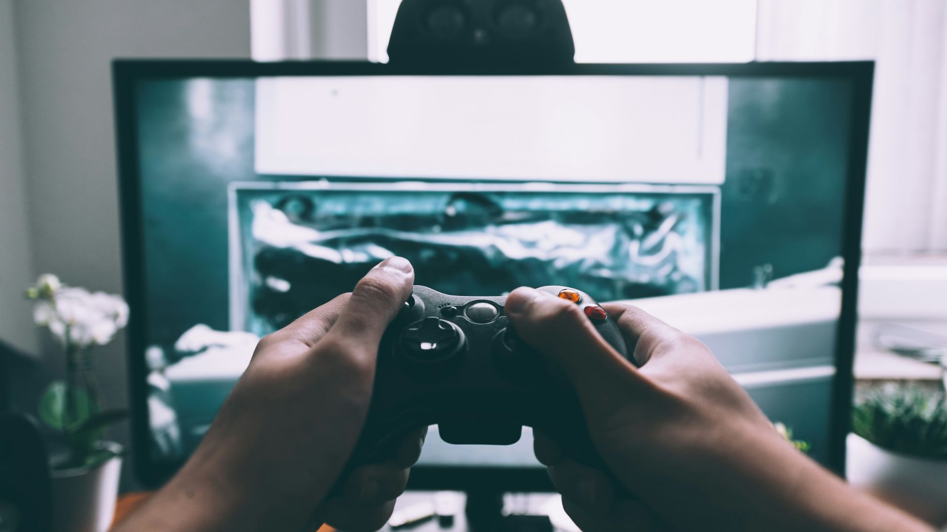 person holding game controller in-front of television