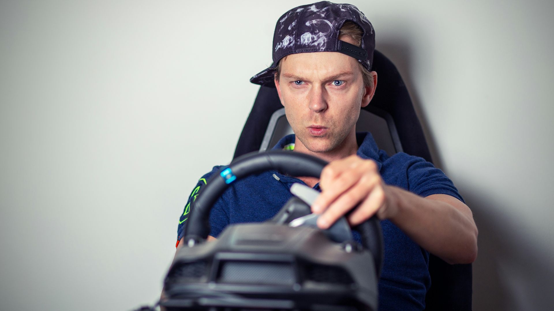 man in blue crew neck t-shirt wearing blue and white cap sitting on black office