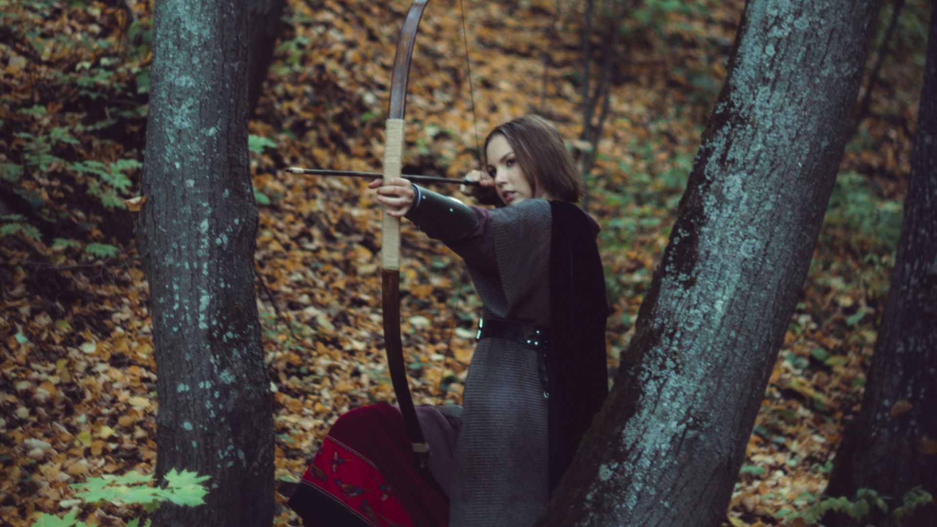 a woman with a bow and arrow in the woods