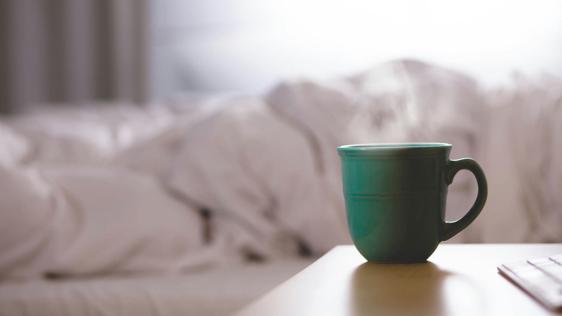 green ceramic mug on wooden desk