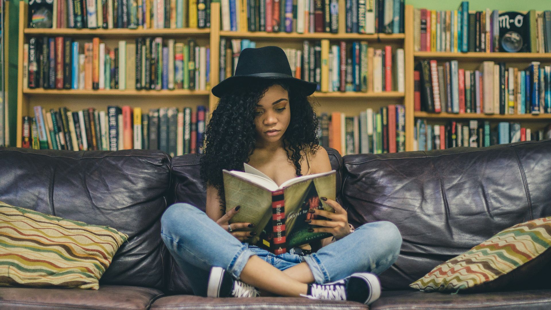 woman reading a book while sitting on black leather 3-seat couch
