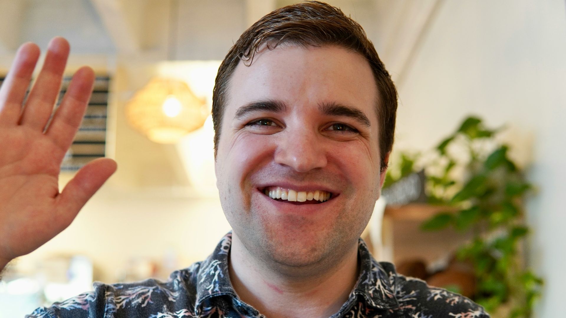 a man smiling and holding up a peace sign