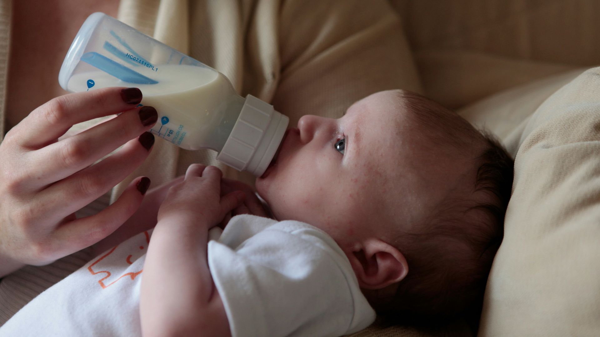 a woman feeding a baby with a bottle of milk