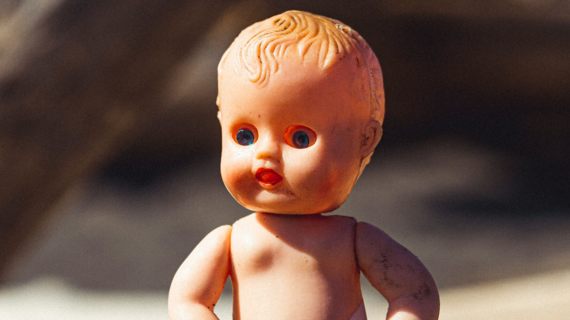 baby doll in blue denim dungaree on brown rock