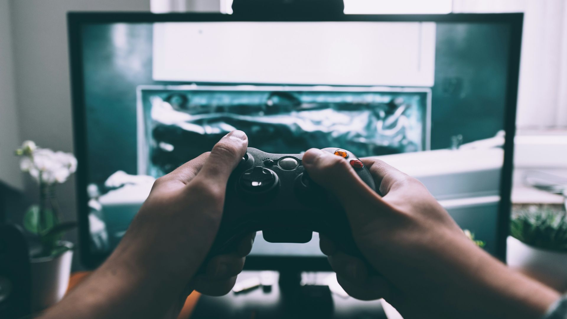 person holding game controller in-front of television