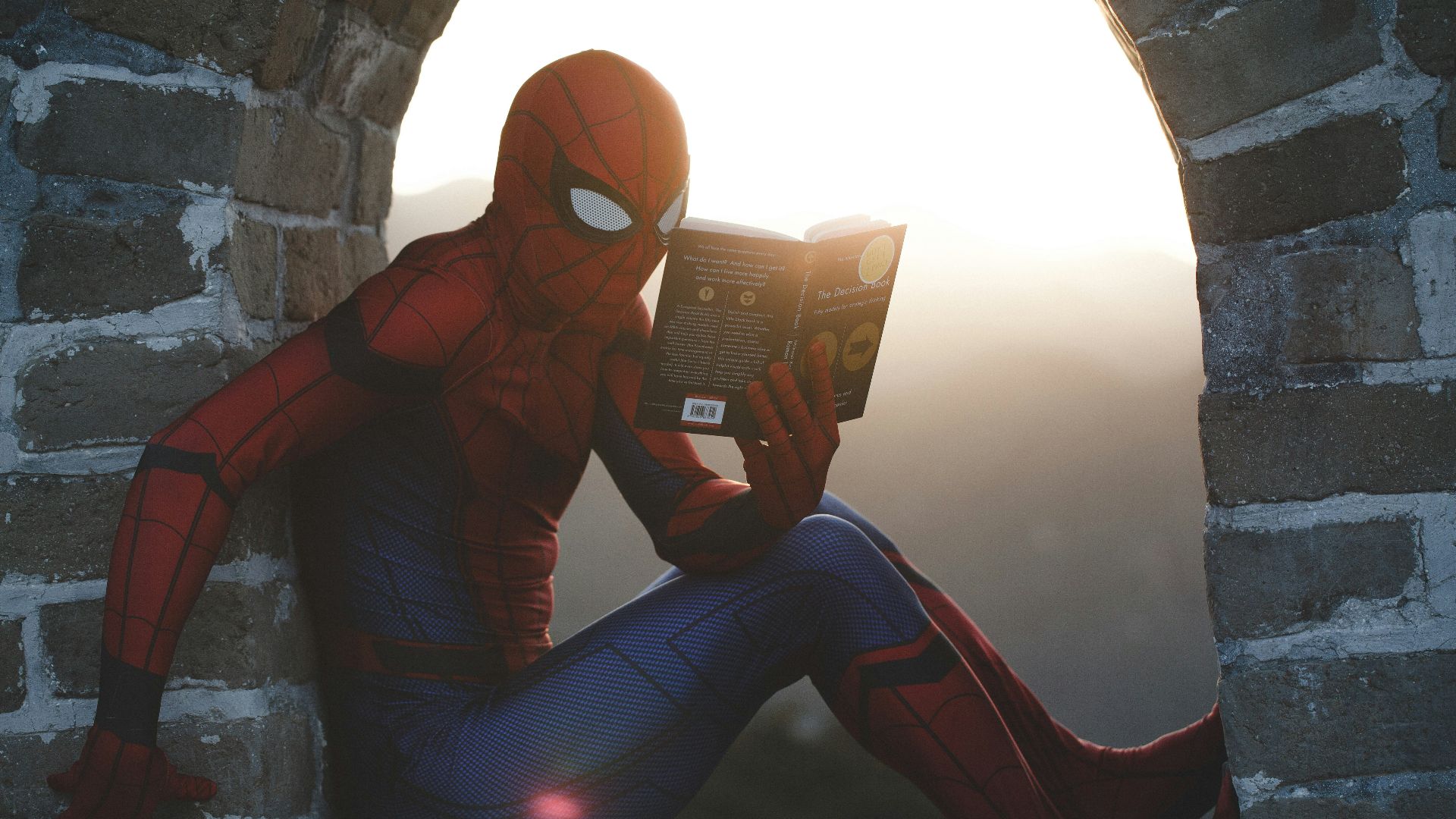 Spider-Man leaning on concrete brick while reading book