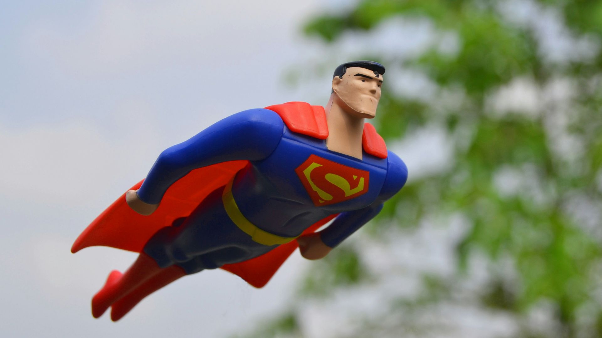 Superman flying near green grass