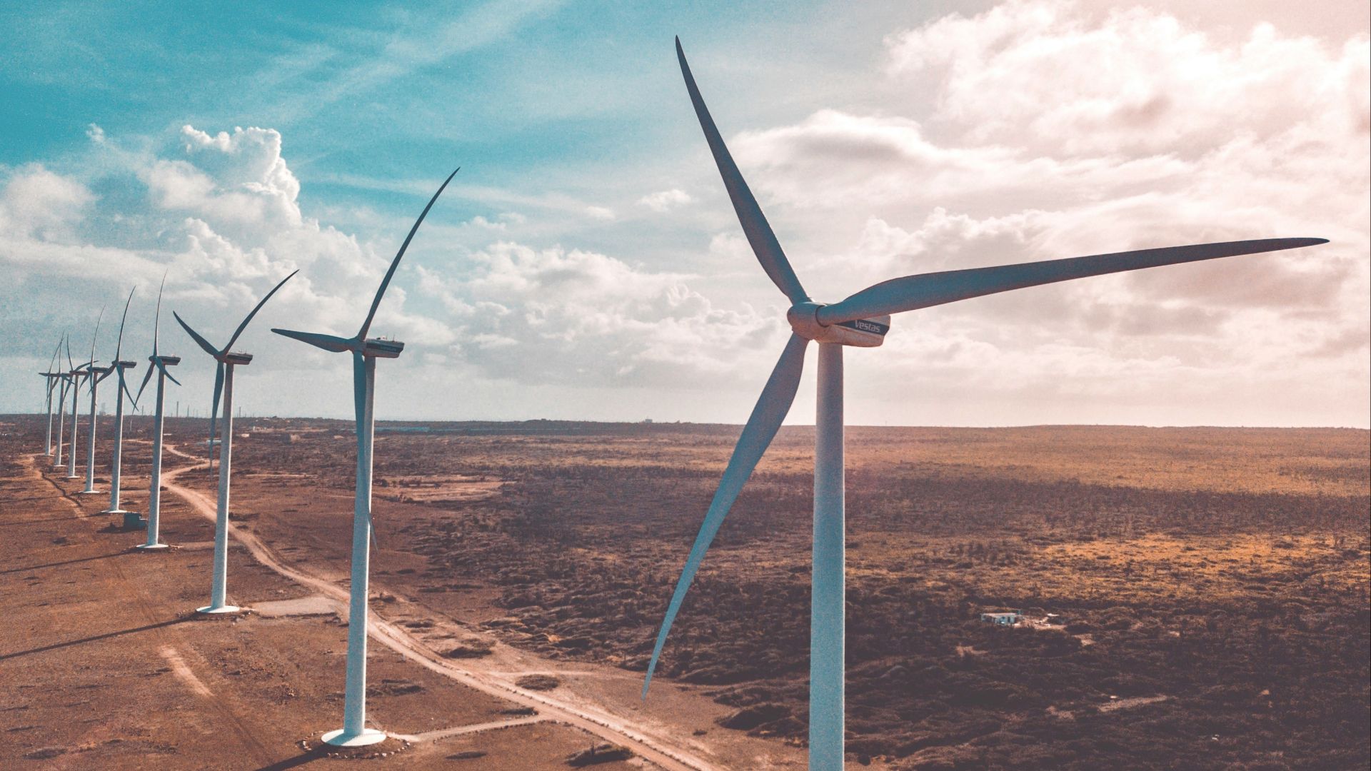 wind turbines on brown sand under white clouds and blue sky during daytime