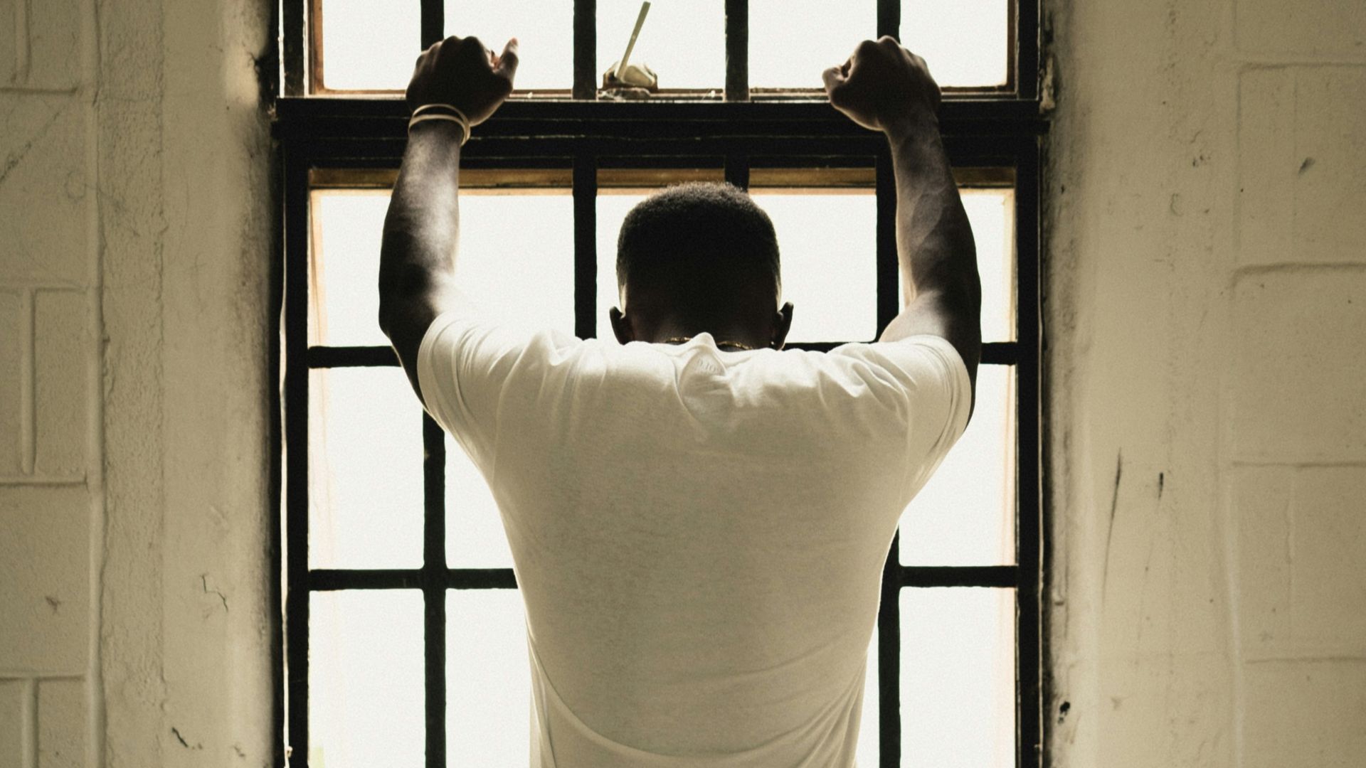 man in white t-shirt standing in front of window
