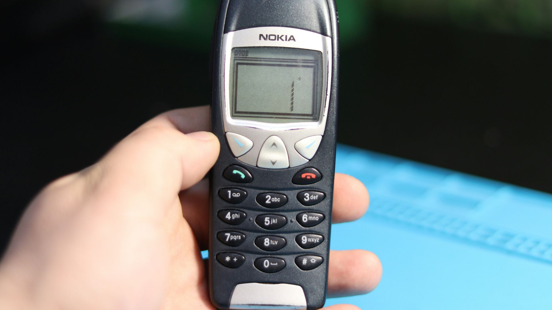 A hand is holding an old nokia cell phone.