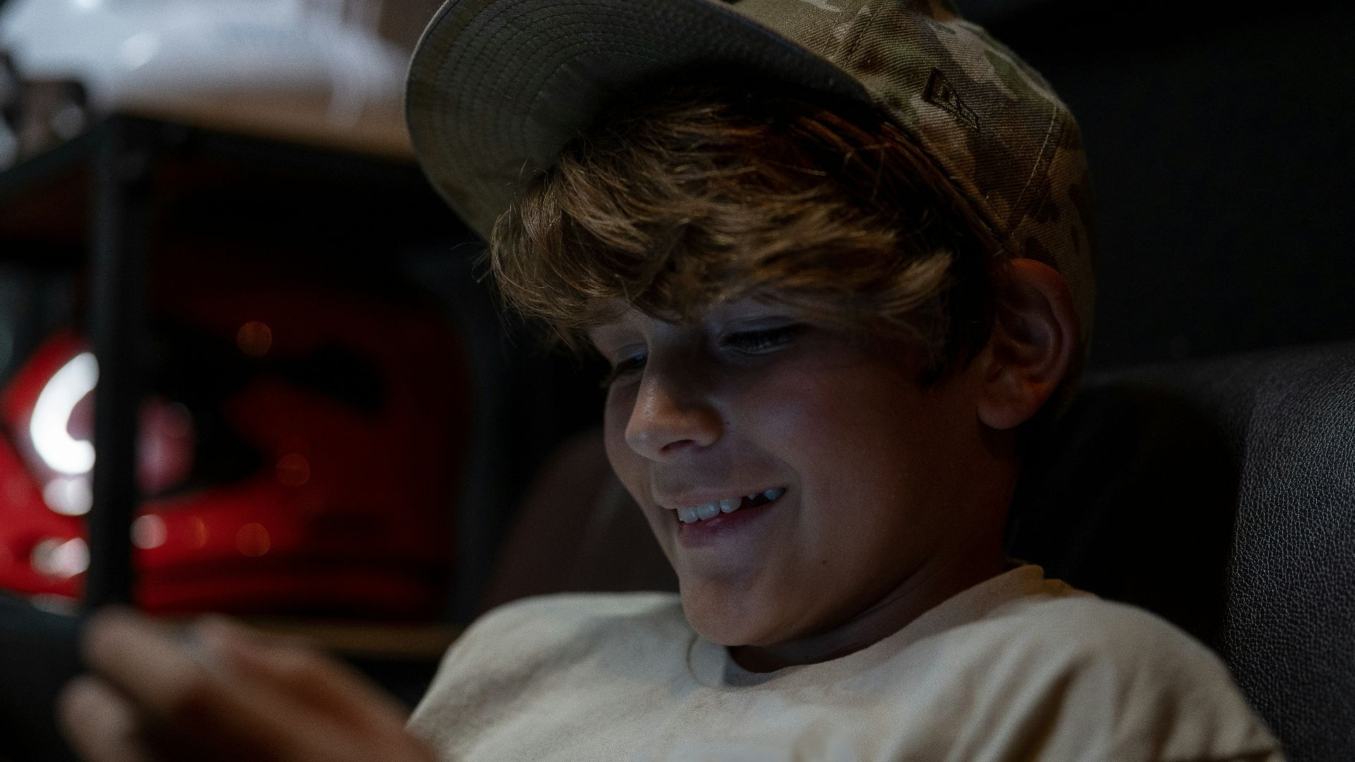 a young boy sitting in a chair looking at a cell phone