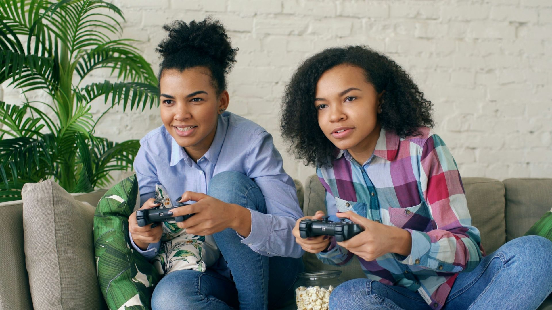 Two young women playing video games on a couch.