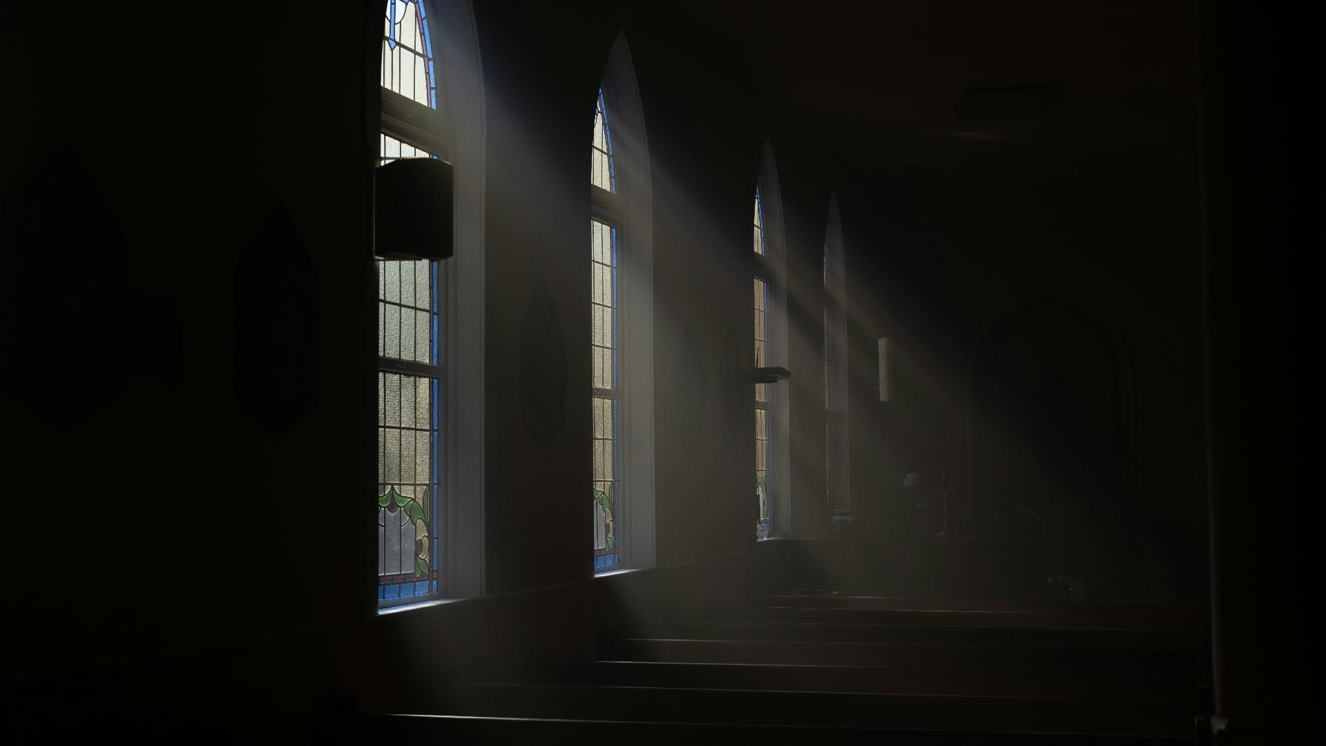 a dark room with sunlight streaming through the windows