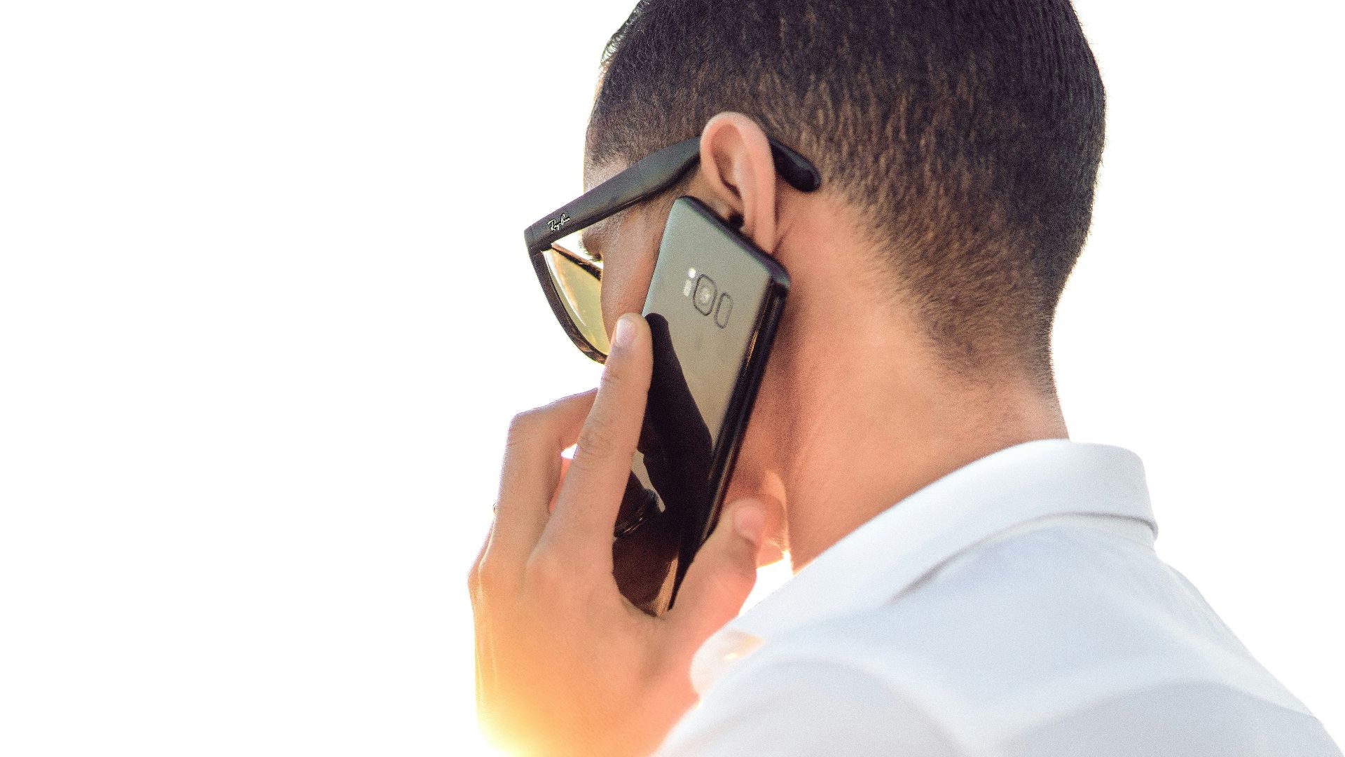 man holding smartphone standing in front of calm body of water