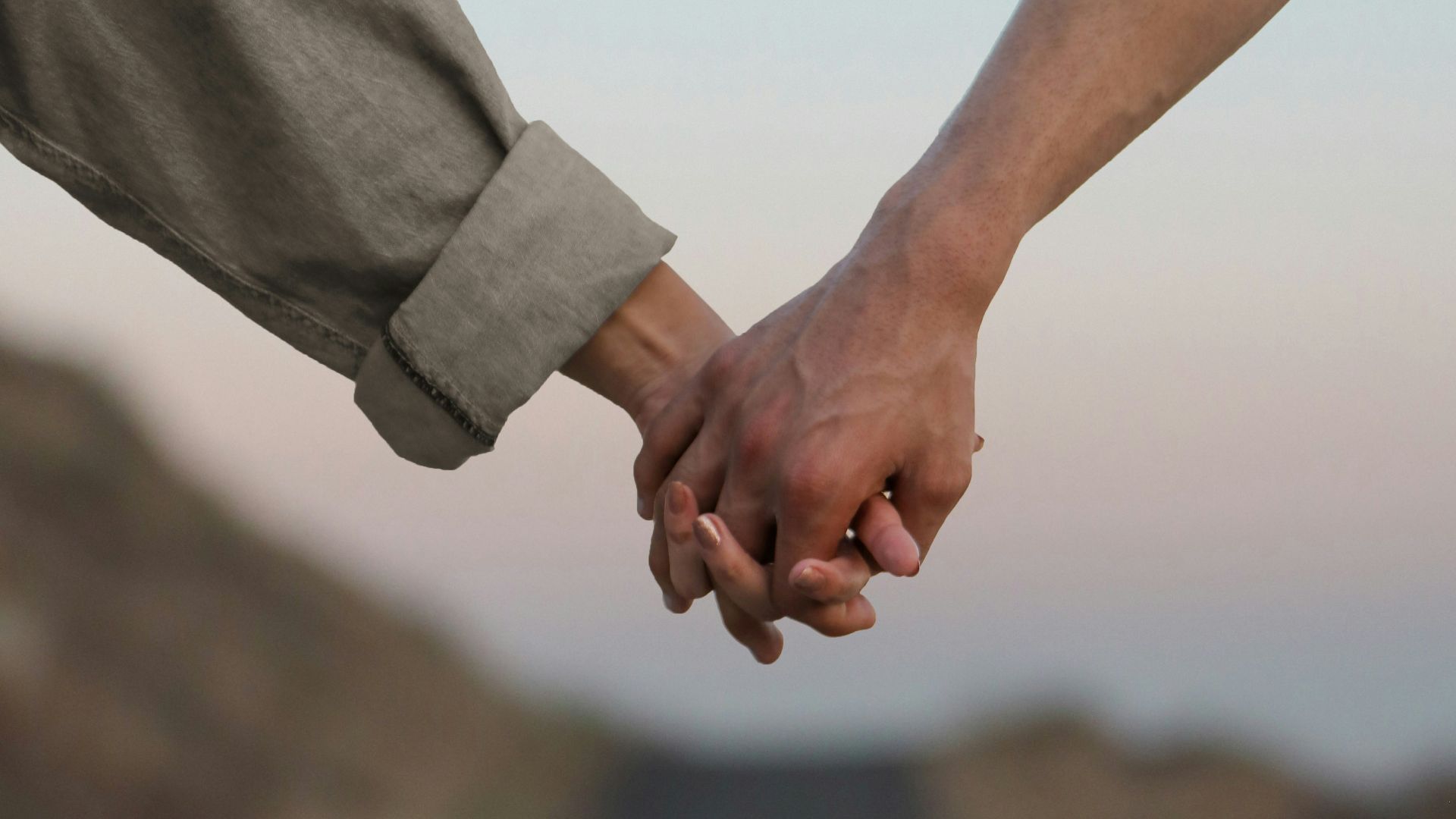 person in gray long sleeve shirt holding hands