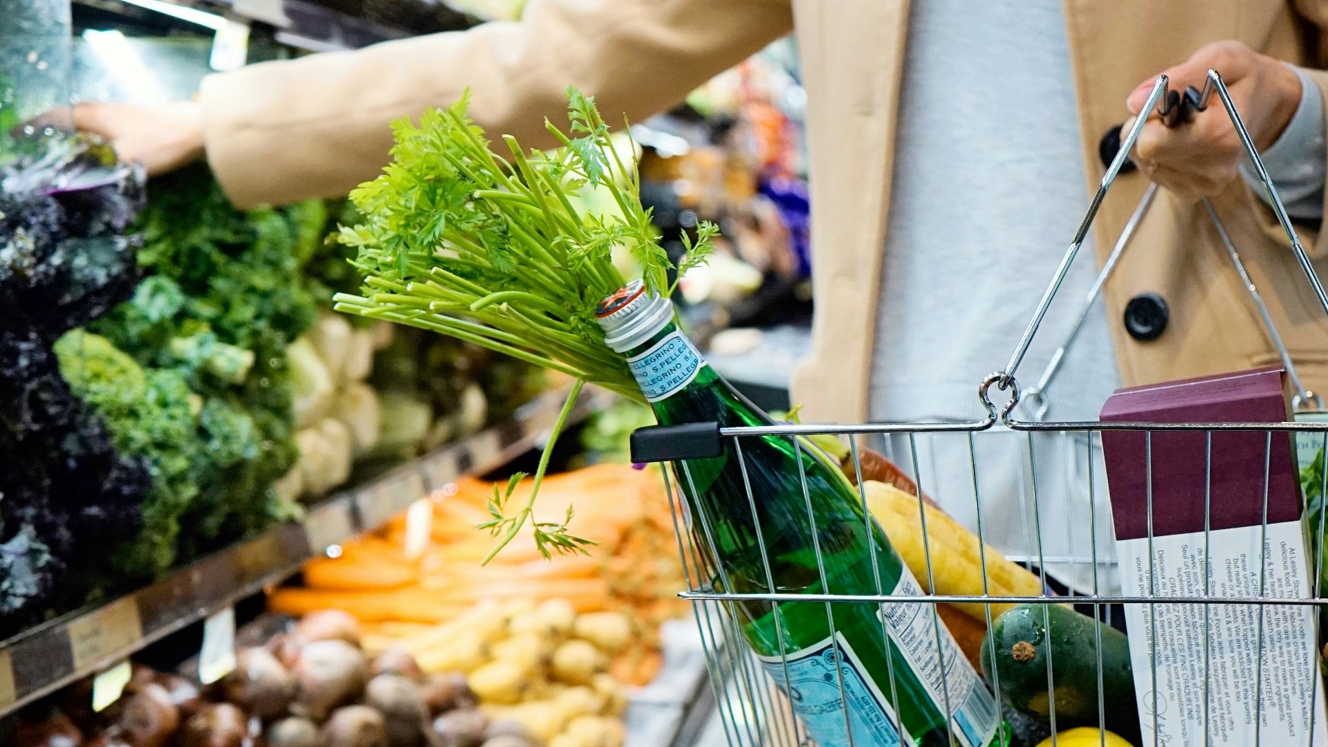 woman in white coat holding green shopping cart