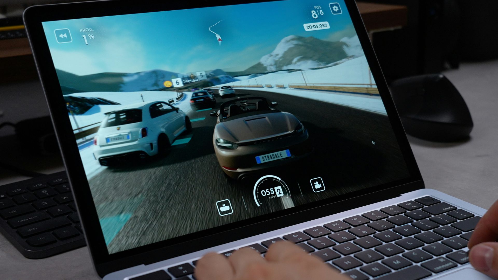 Person playing a racing game on a laptop.