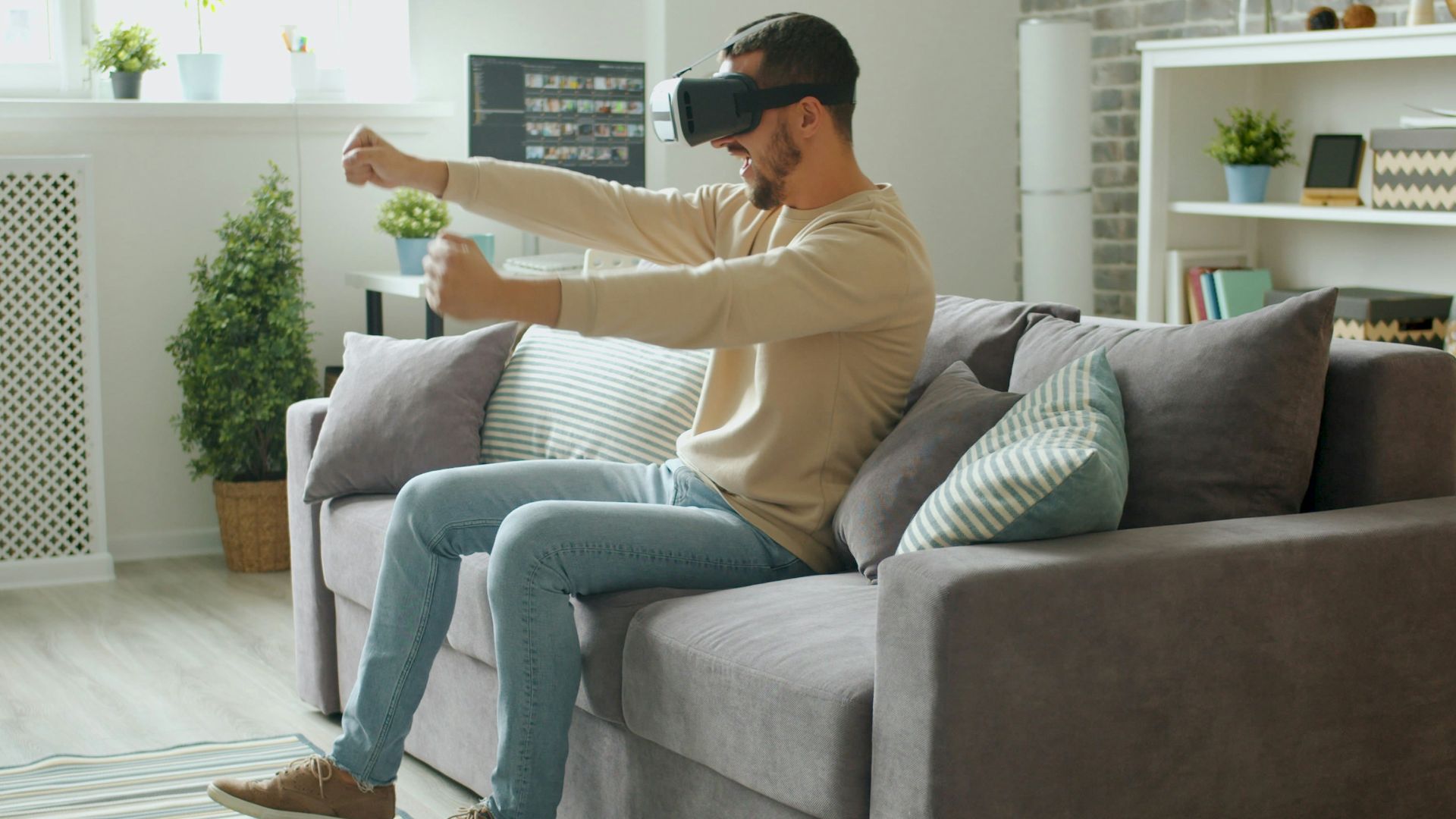 Man wearing vr headset playing a game on couch.