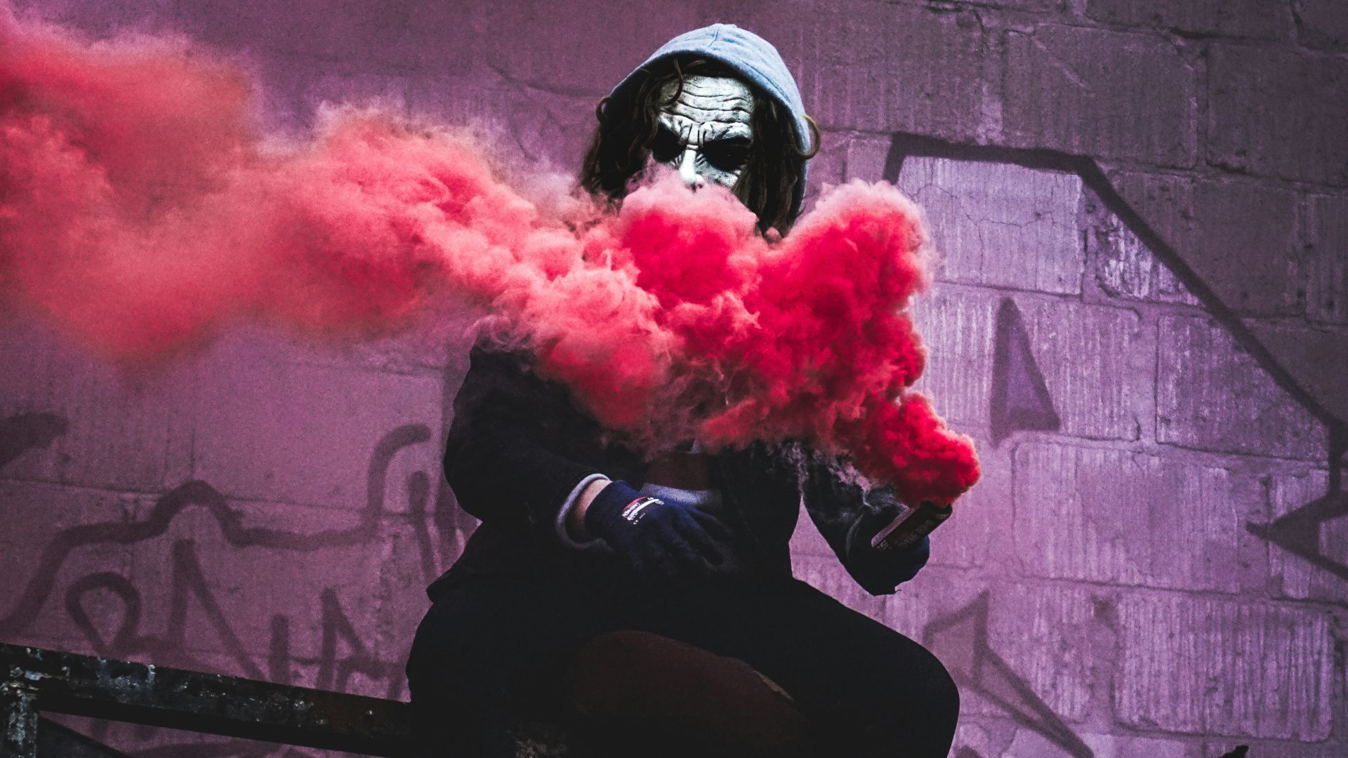 man sitting while holding red smoke signal