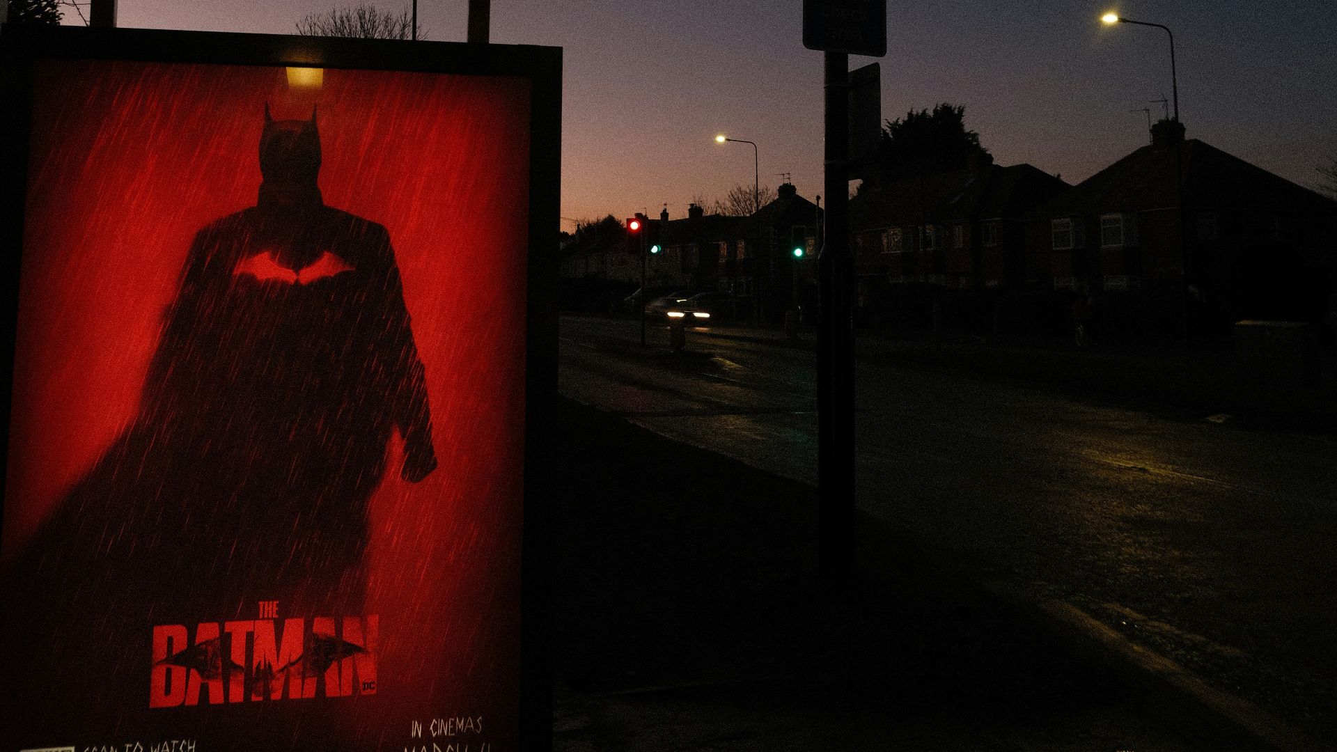 a batman movie poster on the side of the road