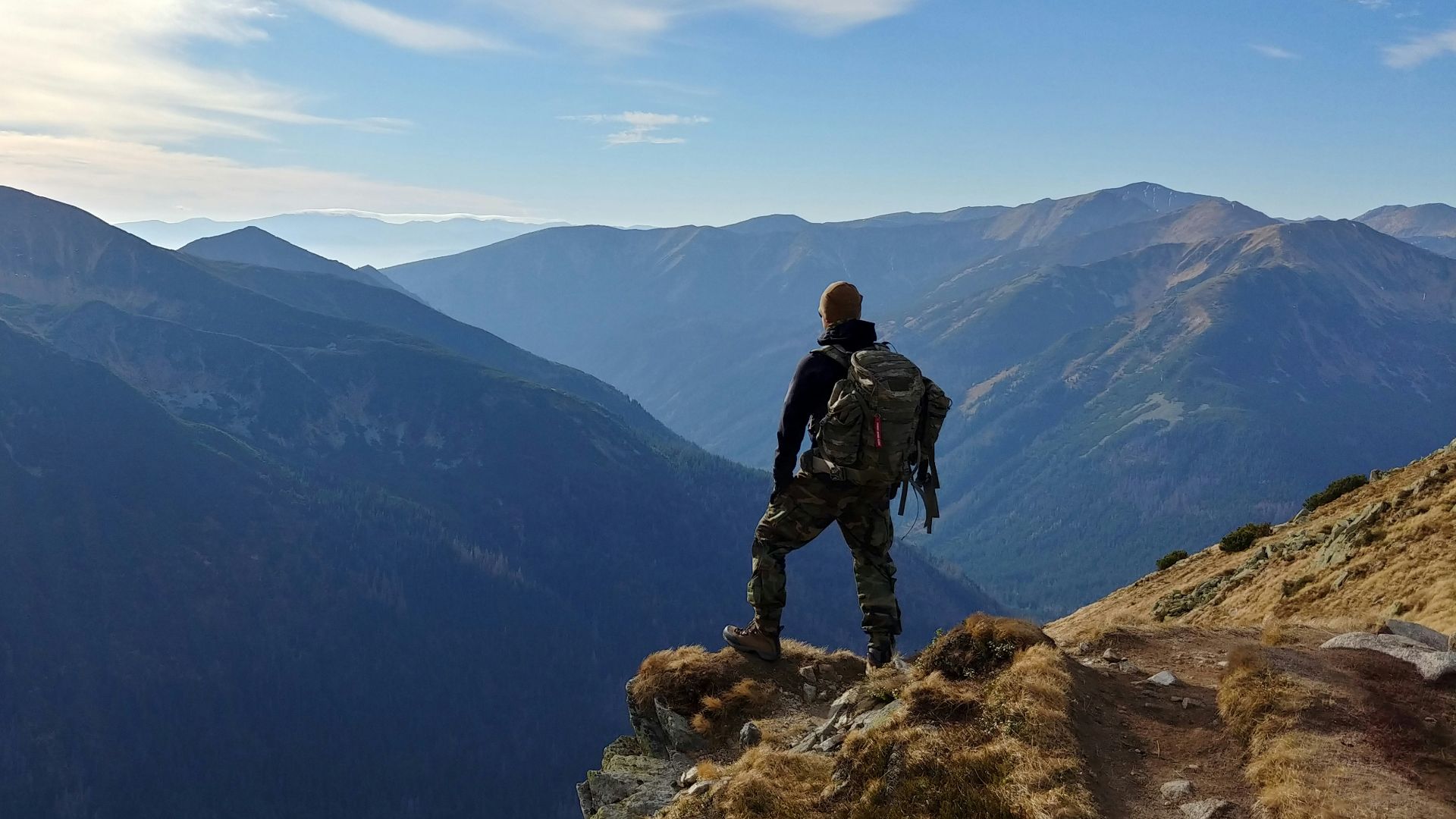 man on top of mountain under blue sky