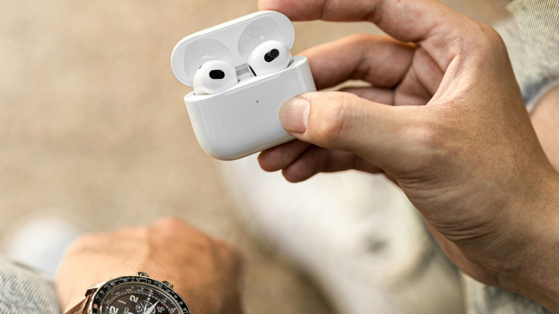 a person holding an airpods in their hand