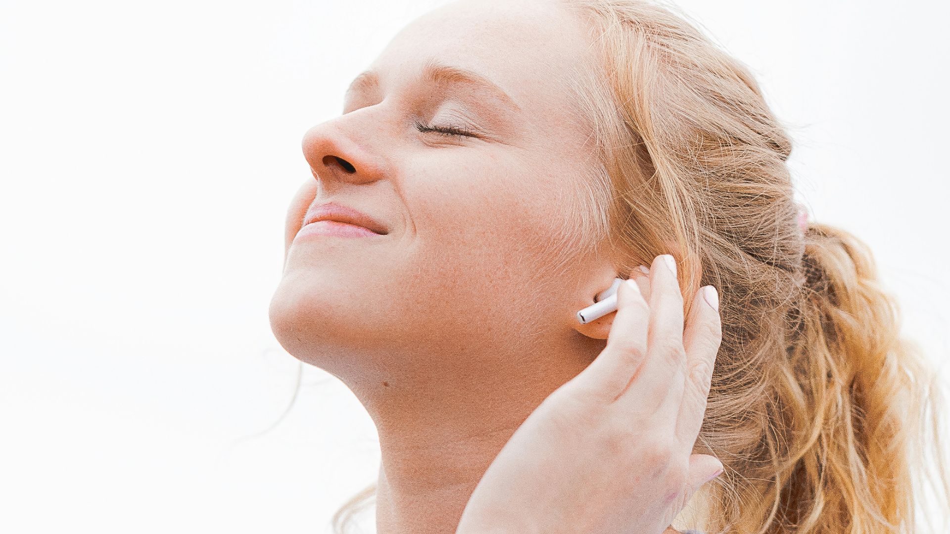 woman in white crew neck shirt covering her face with her hand