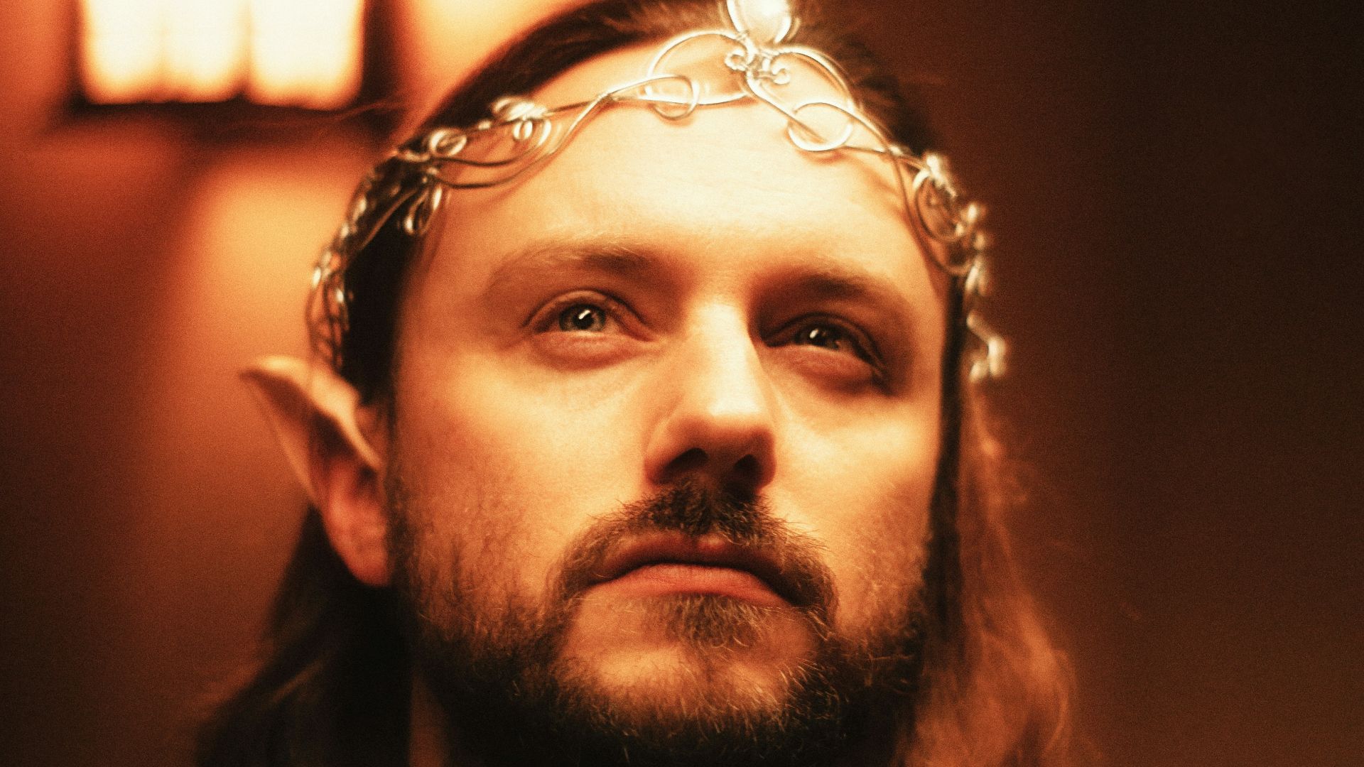 An elf with a crown looks up towards the light.