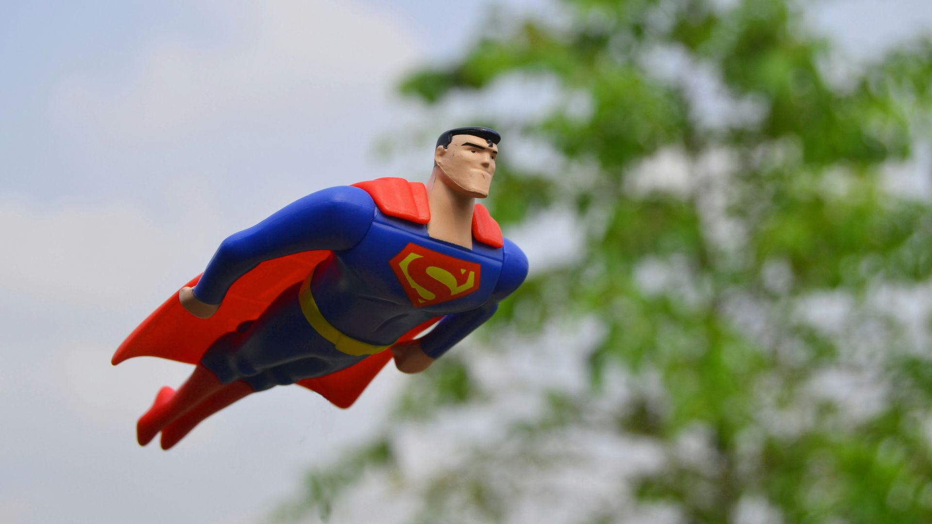 Superman flying near green grass