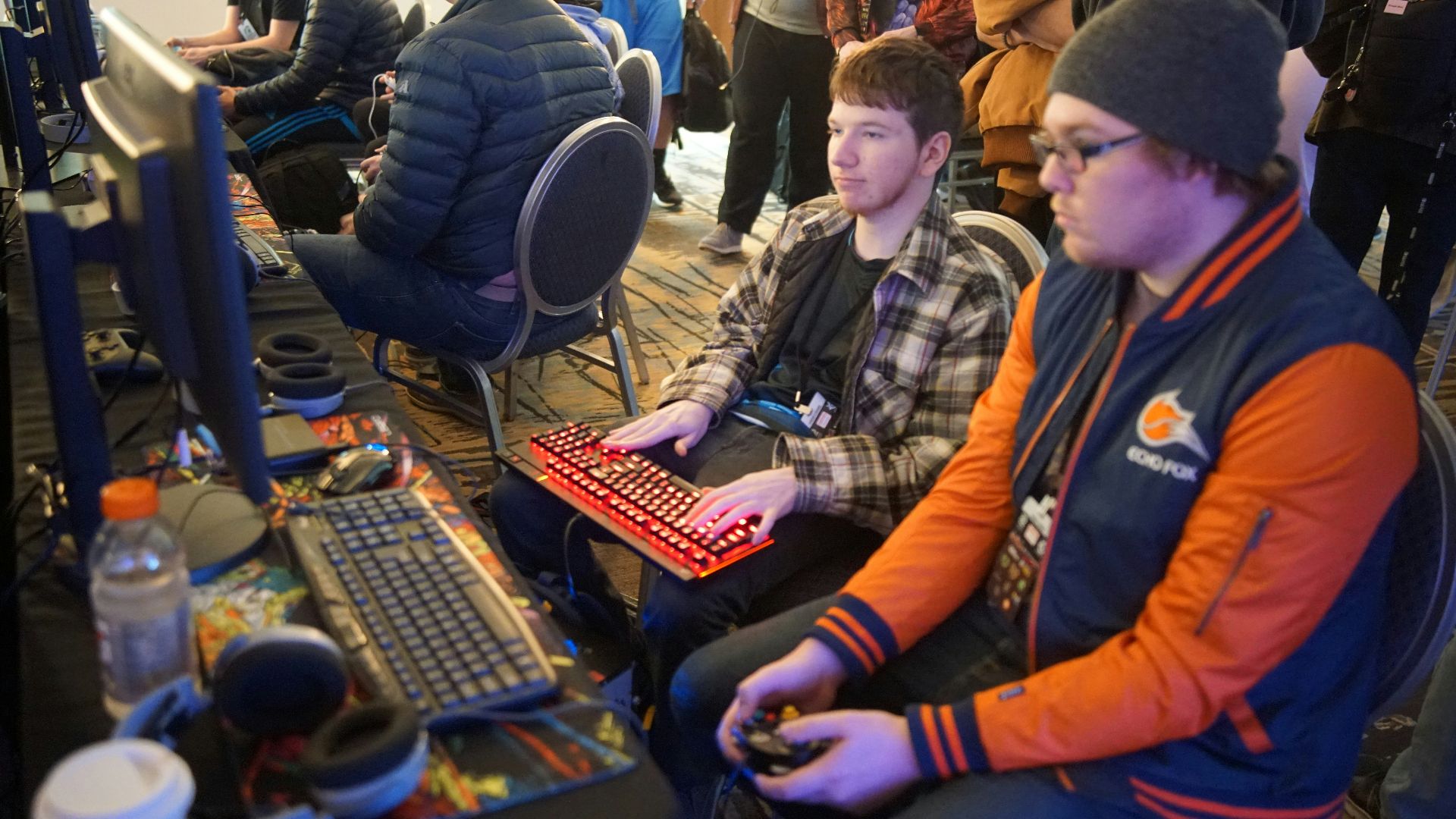 man using video game control pad beside man using computer keyboard sitting and playing video games