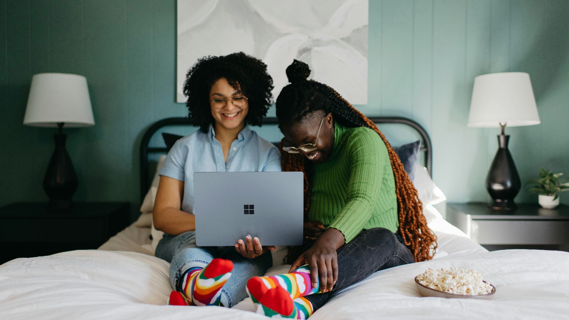 a woman sitting on a bed using a laptop