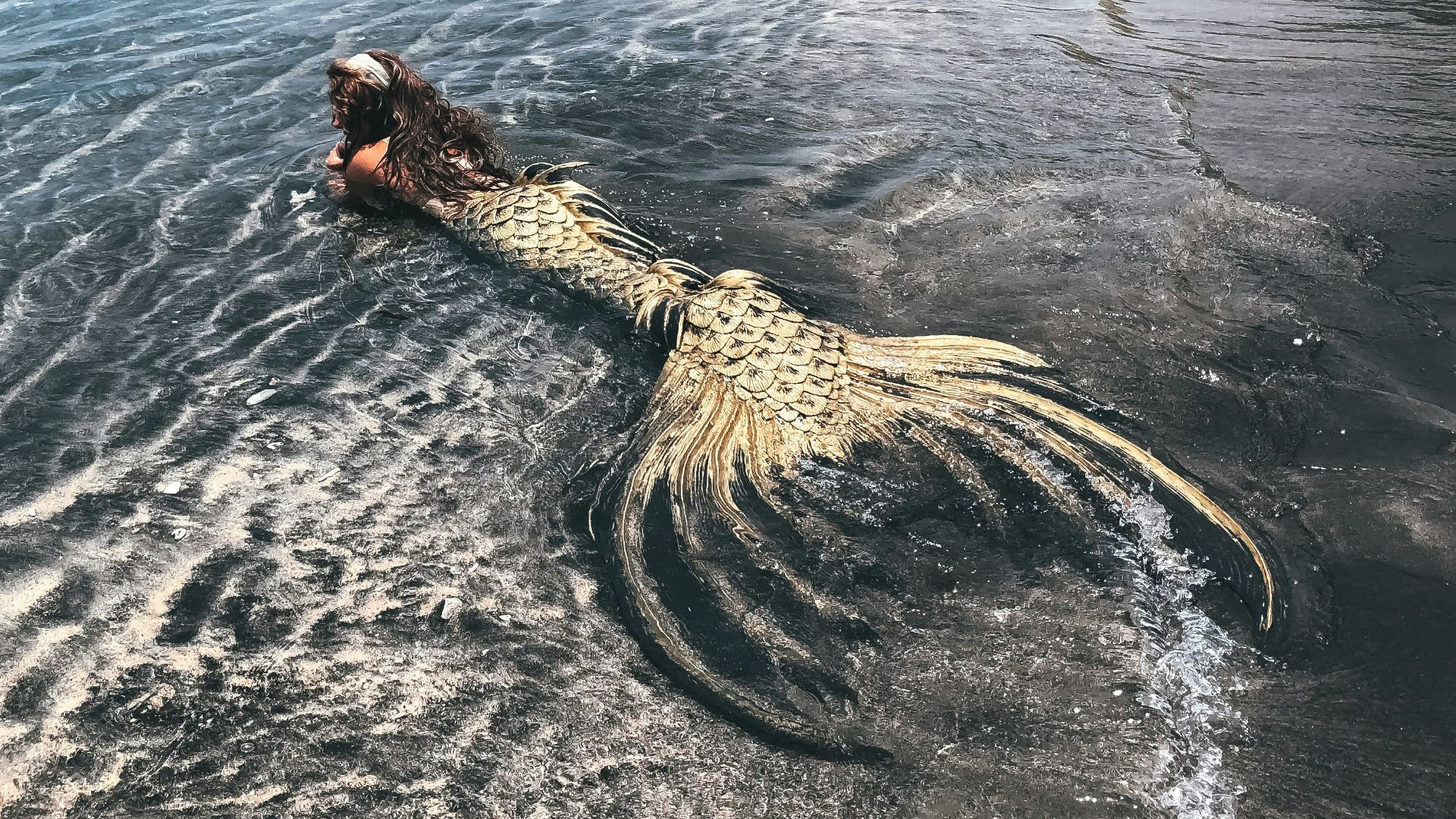 woman in black and white dress on brown rock formation on sea during daytime