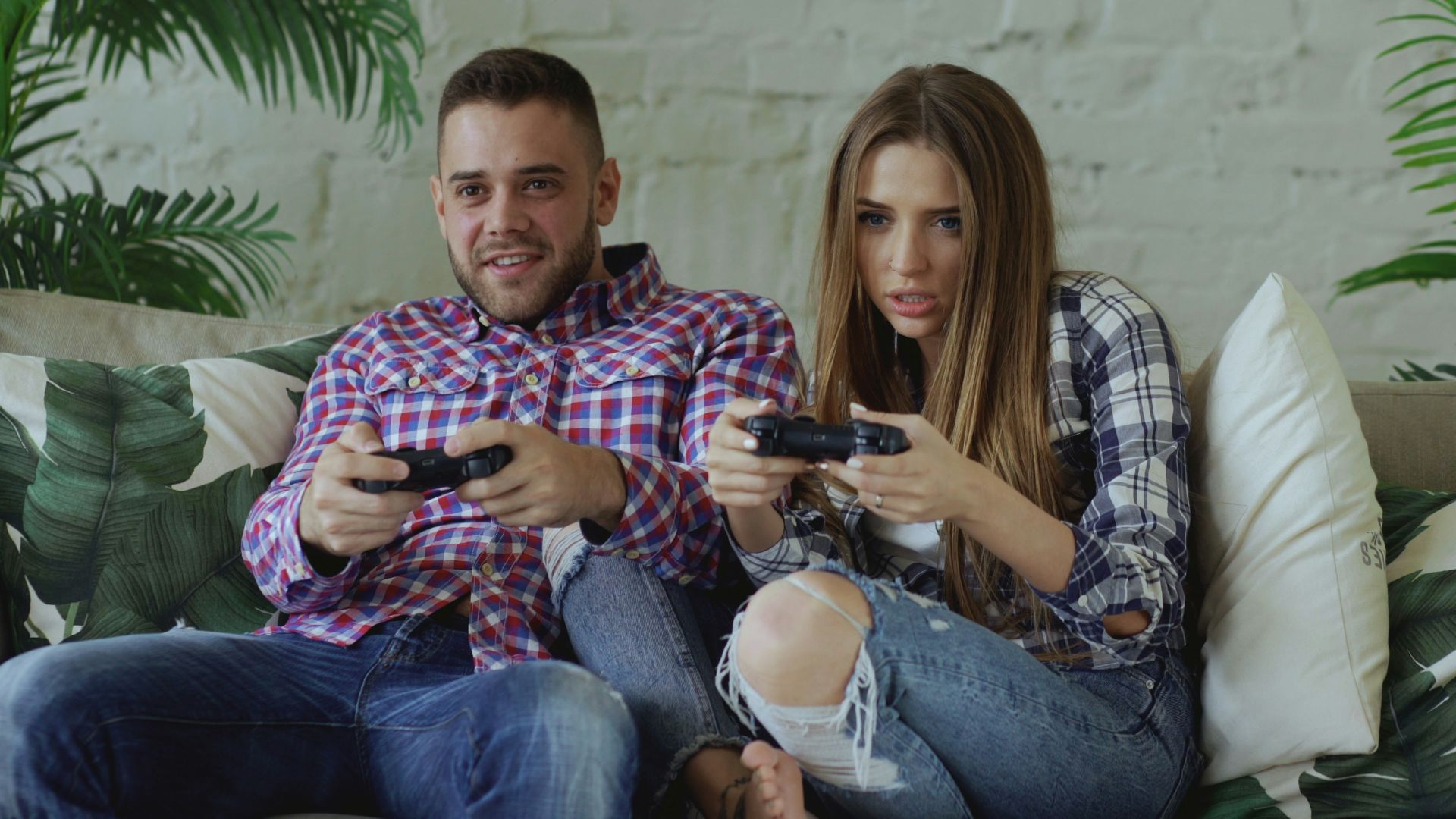 Couple playing video games on sofa