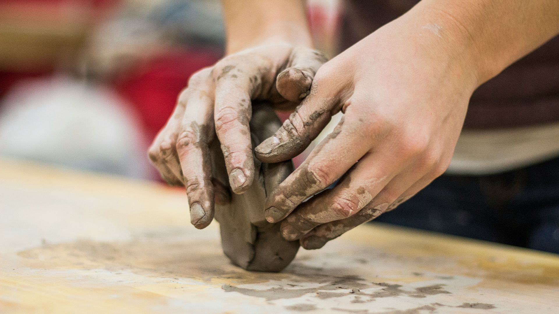 A clay stained hand of a potter engaging in a craft work of pottery or molding