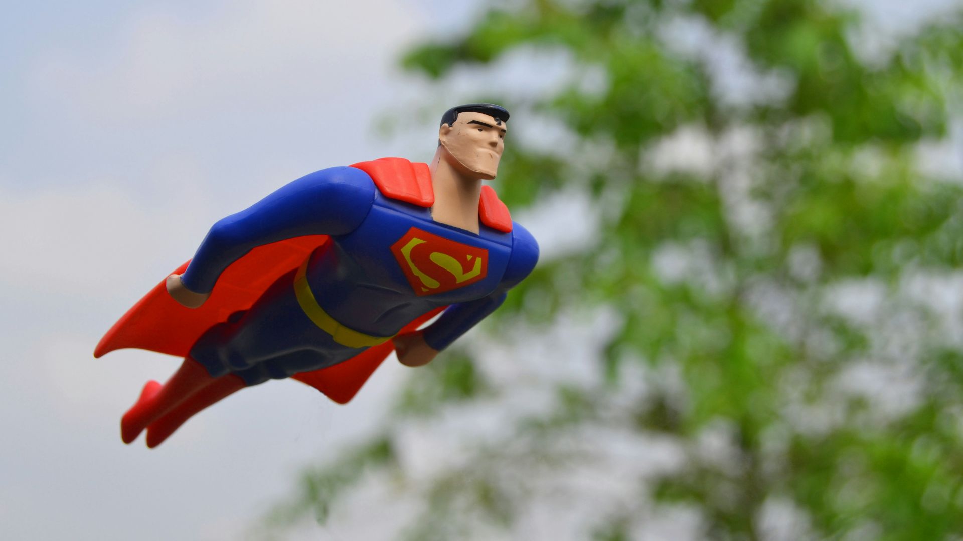 Superman flying near green grass