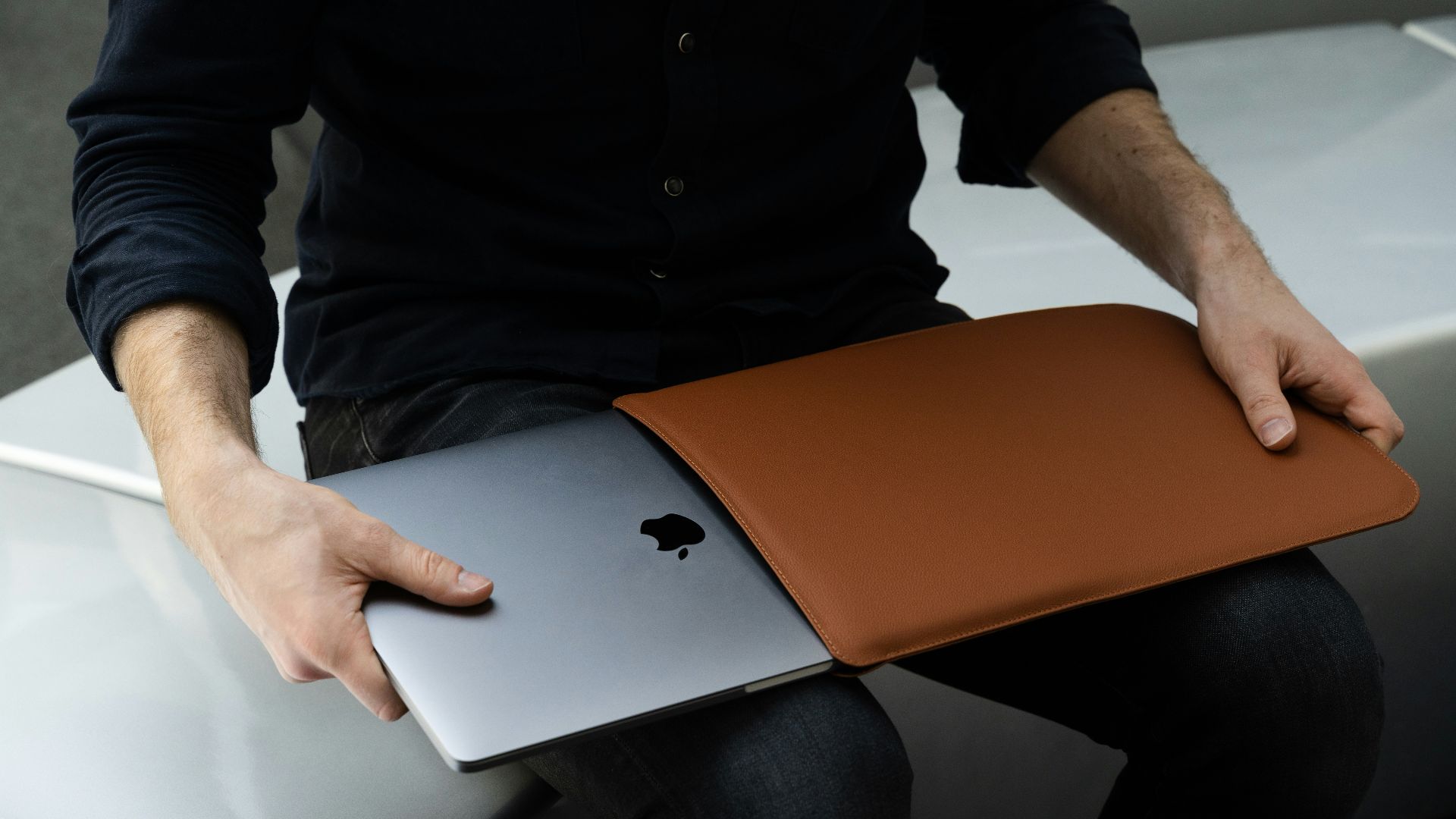 a man sitting on a chair holding a laptop