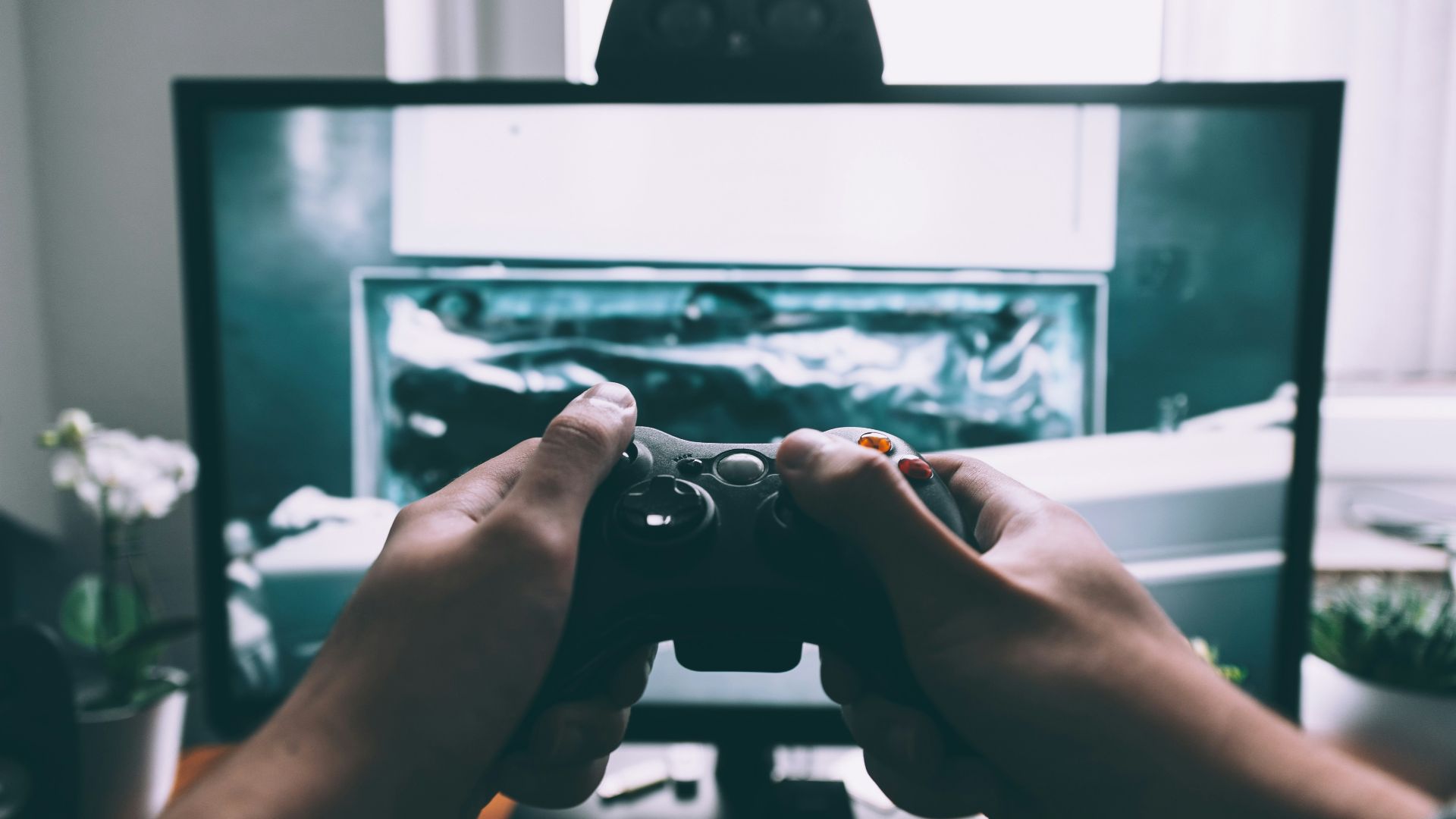 person holding game controller in-front of television