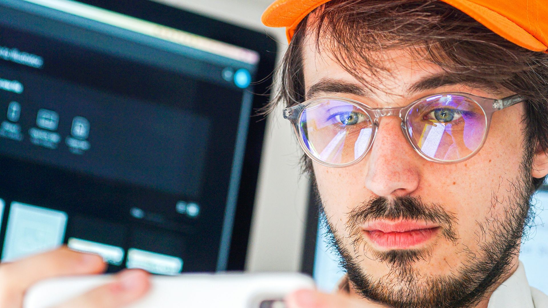 man in orange cap and black framed eyeglasses